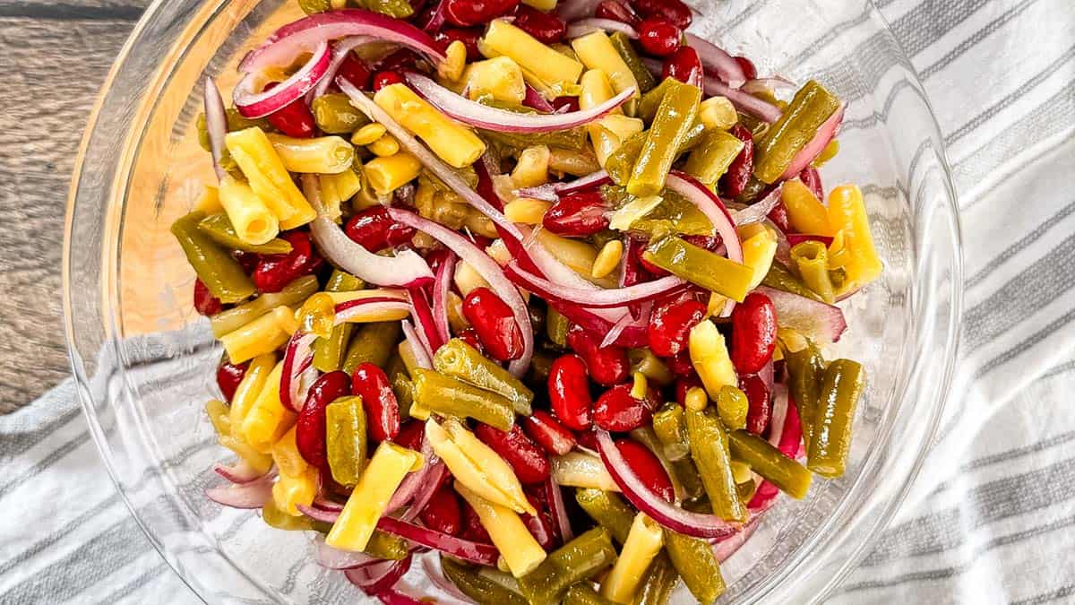 Classic three bean salad with red onion and tangy dressing in a serving bowl.