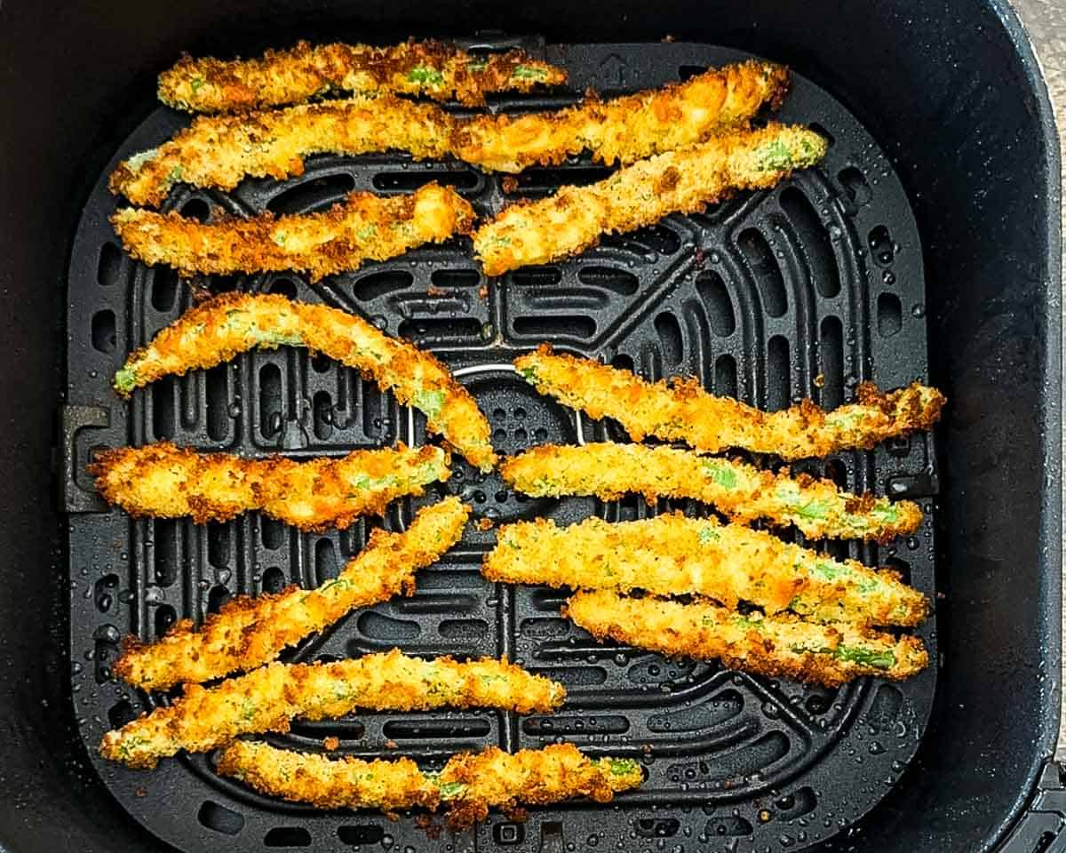 The air fried green bean fries crispy and golden brown in the air fryer basket.