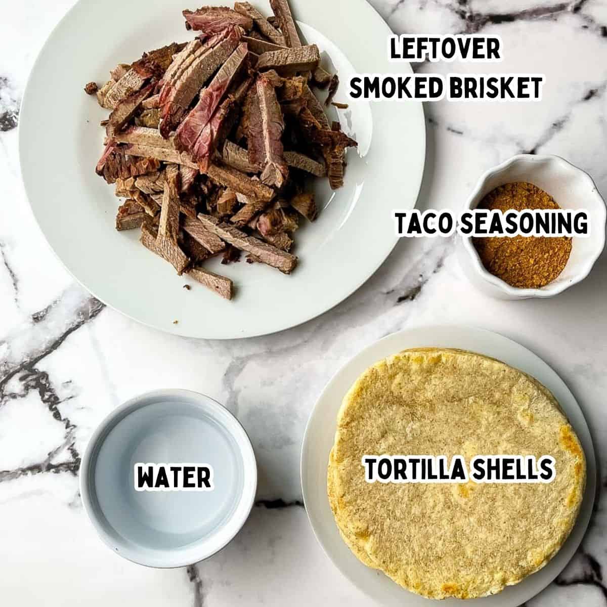 Labeled ingredients for smoked brisket tacos including sliced smoked brisket, taco seasoning, water, and tortillas on a marble countertop.