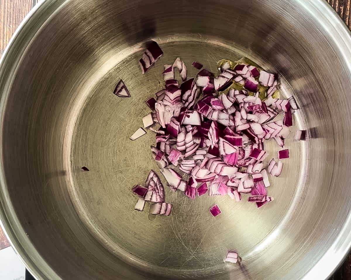 Diced red onion sautéing in olive oil in a large pot.