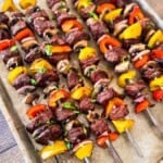 Smoked steak kabobs with top sirloin, mushrooms, bell peppers, and red onion on metal skewers.