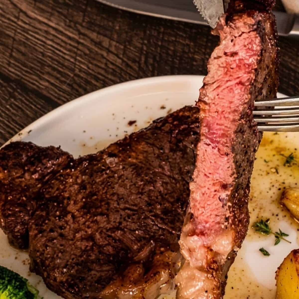Sliced air fryer ribeye steak showing a juicy pink center and browned crust.
