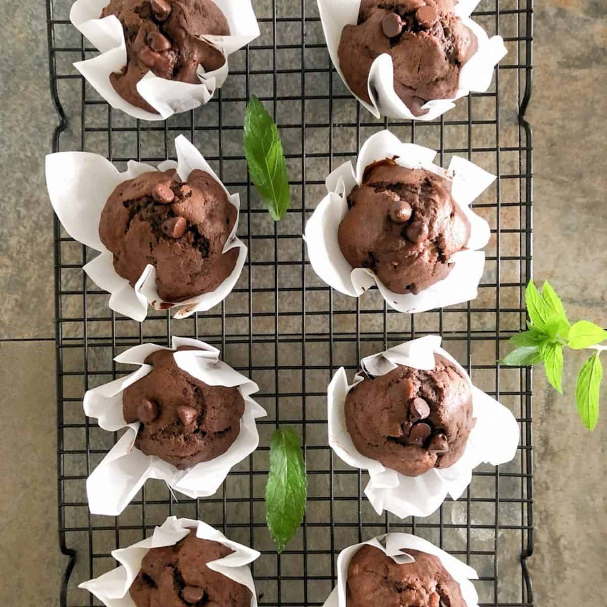 Baked double chocolate banana muffins cooling on a rack.