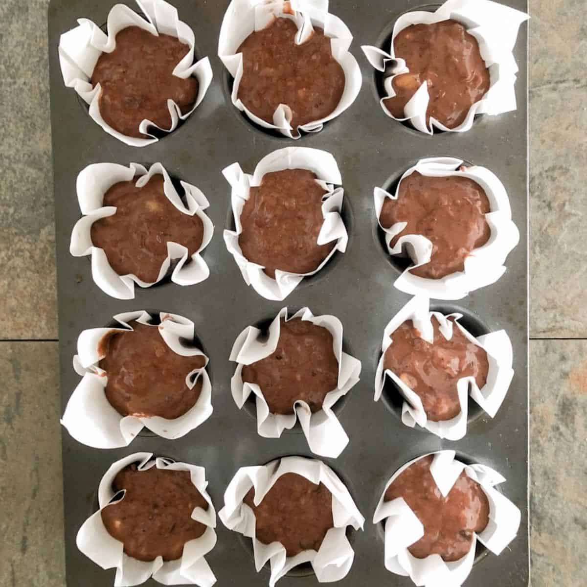 Batter for double chocolate banana muffins spooned into muffin cups.