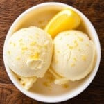 Ninja Creami lemon ice cream in a white bowl with lemon zest and fresh lemon slices.