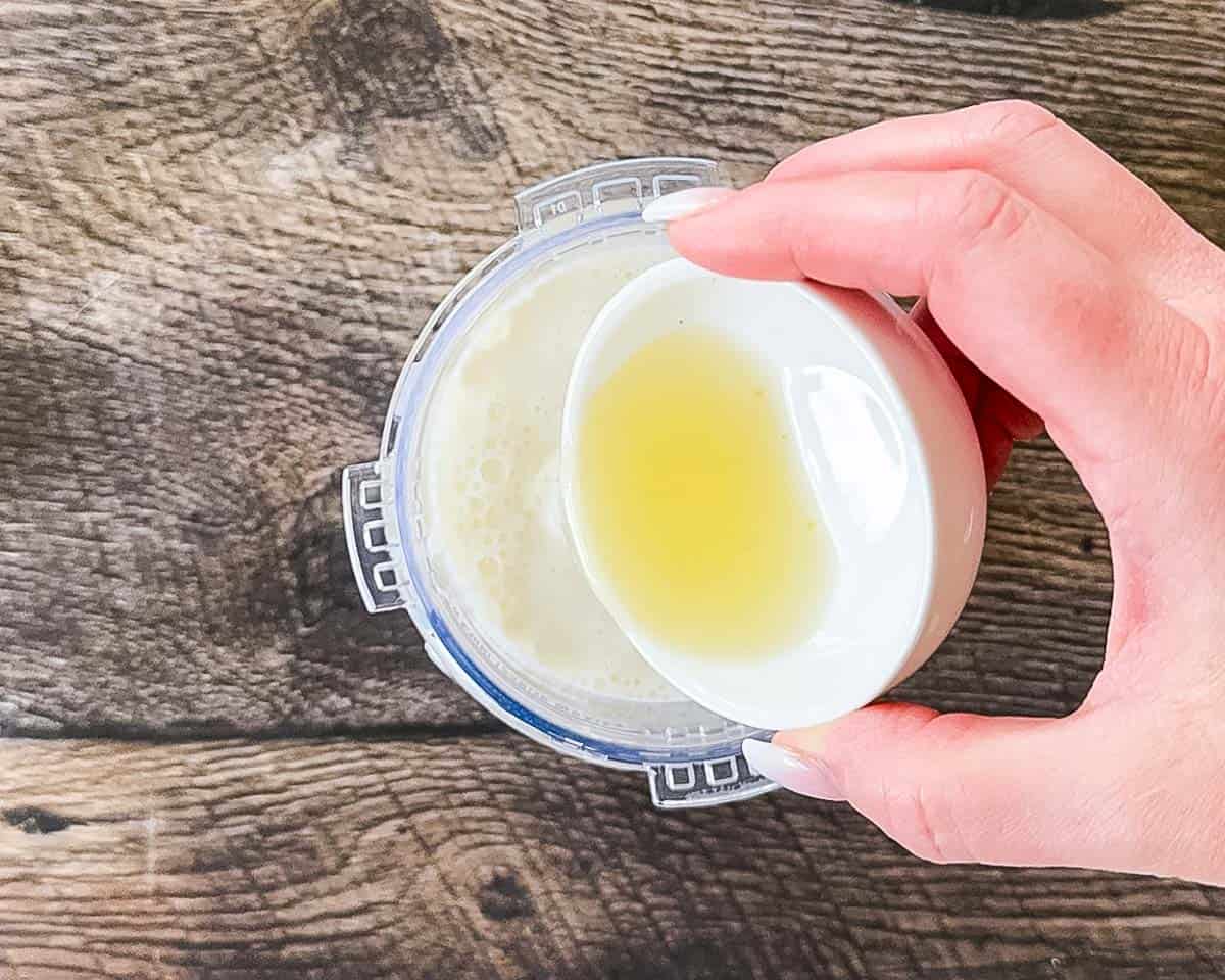 Pouring fresh lemon juice into a Ninja Creami pint jar.