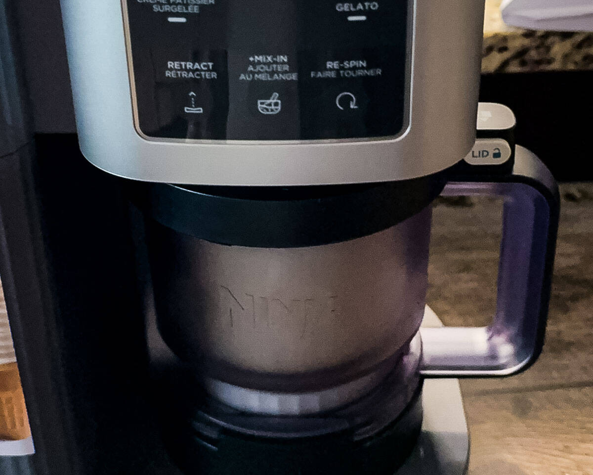 Frozen lemon ice cream pint locked into a Ninja Creami machine before spinning.