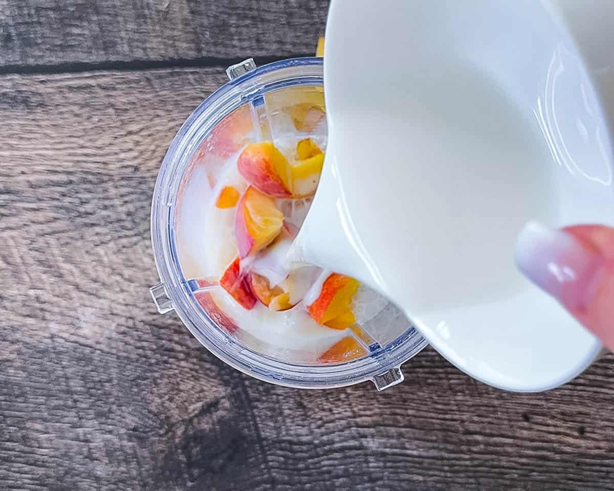 Adding the peach ice cream ingredients to a blender.