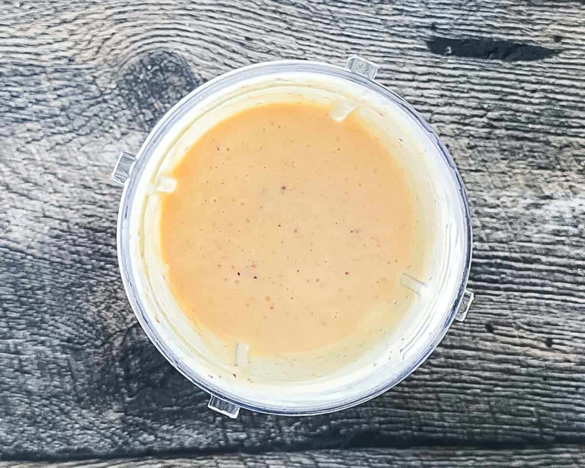 Blended peach ice cream base in a glass blender, smooth and pale orange.