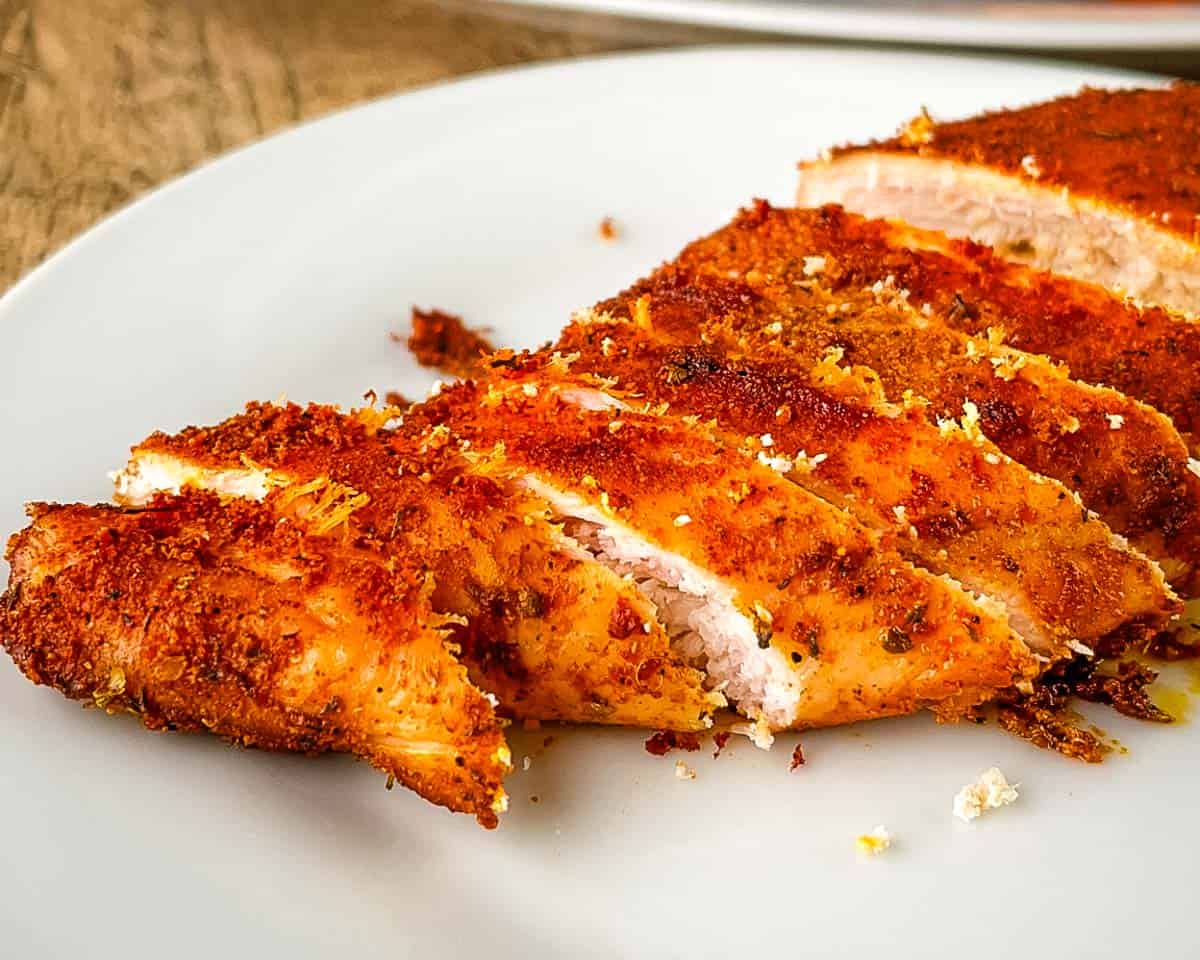 Sliced smoked chicken breast showing the tender and juicy inside on a white plate.
