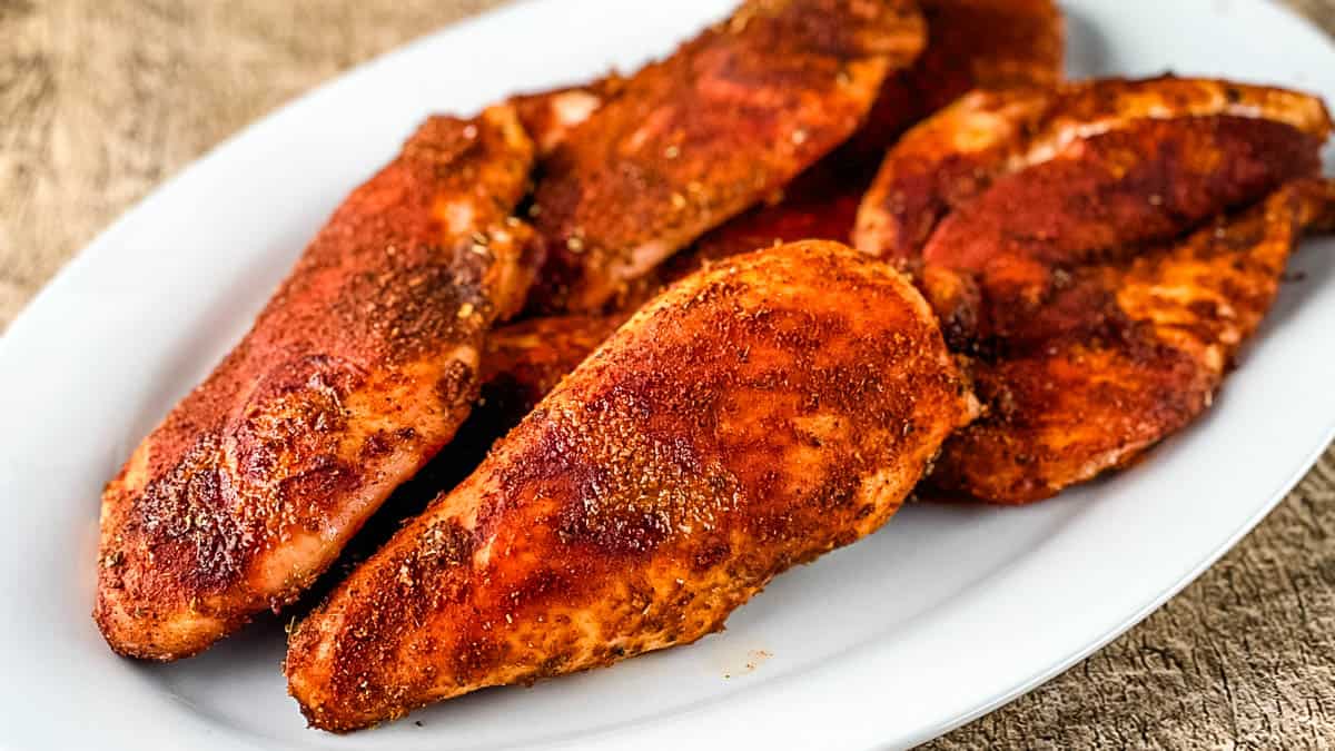 Smoked chicken breast cooked in an electric smoker on a white plate.