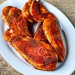 Smoked chicken breasts with Cajun seasoning on a white plate.
