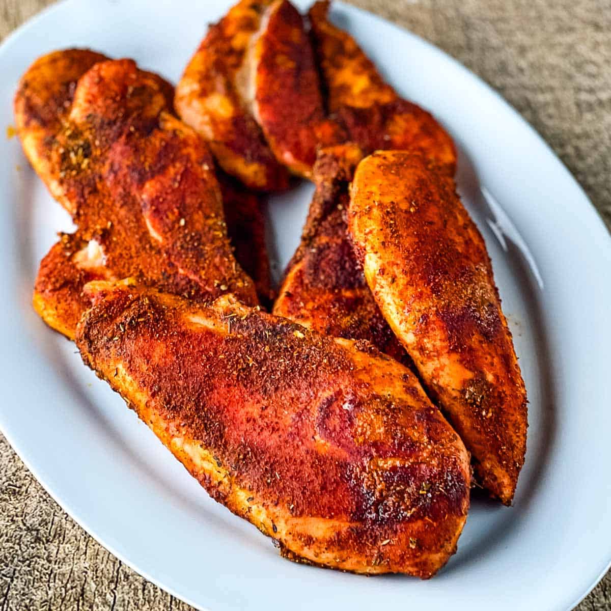Smoked chicken breasts with Cajun seasoning on a white plate.
