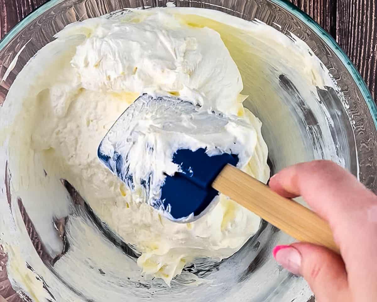 Mixing the cream cheese and Cool Whip filling for classic strawberry pretzel salad before spreading over the pretzel crust.