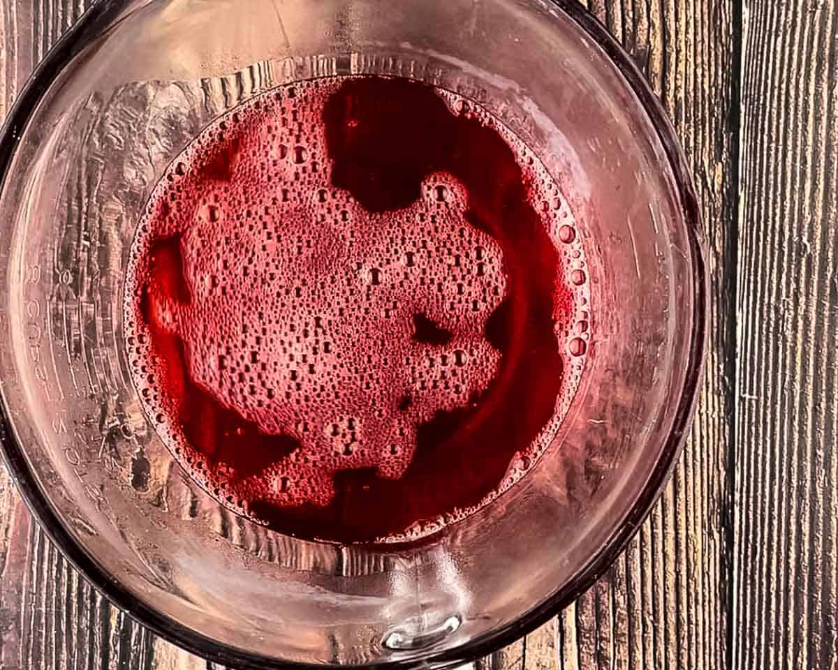 Strawberry Jell-O dissolved in hot water in a glass mixing bowl.