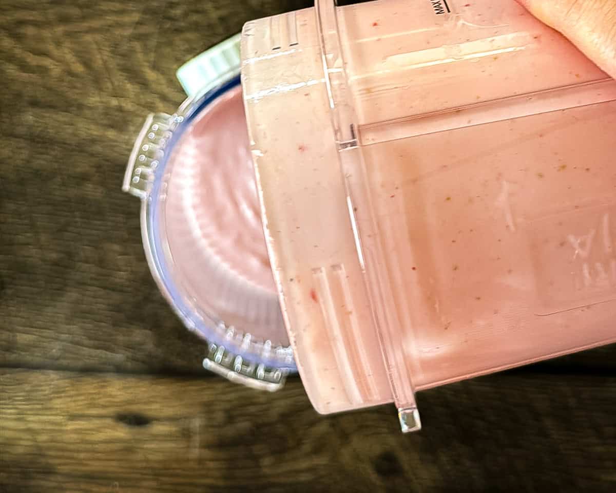 Pouring the blended ice cream mixture into a Ninja Creami pint container.