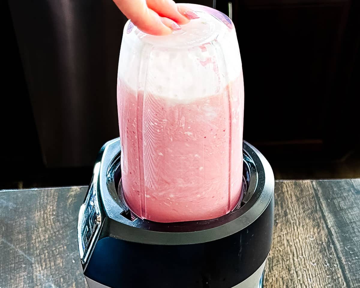 Blending the ingredients for the strawberry cottage cheese ice cream in a blender.