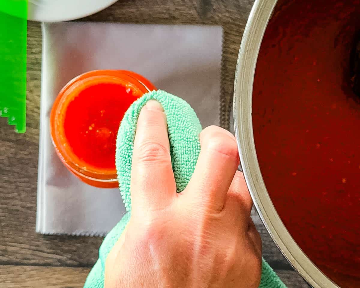 Wiping the rim of a canning jar before applying the lid.