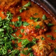 A skillet with chicken paprikash, garnished with fresh herbs.