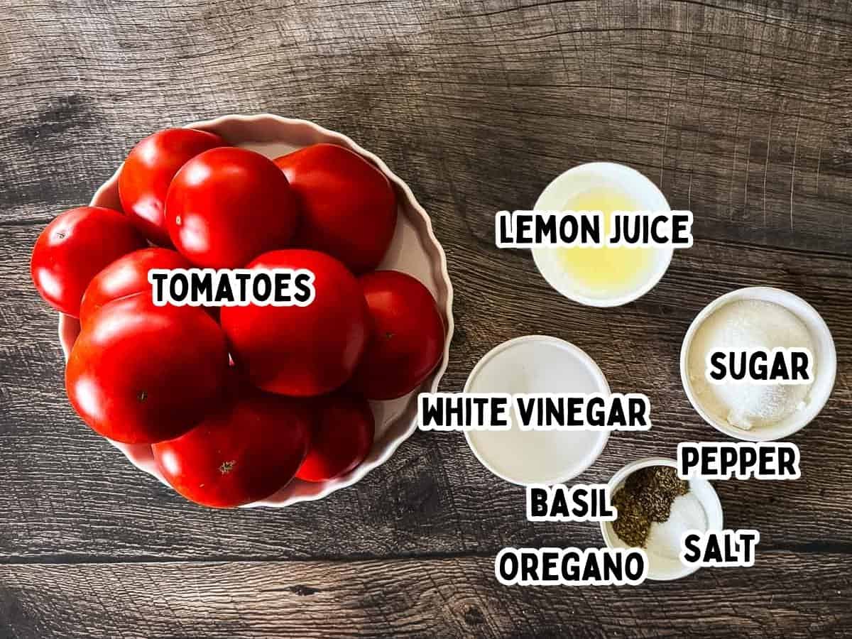 Labeled ingredients for homemade canned tomato sauce including fresh tomatoes, vinegar, basil, oregano, salt, pepper, sugar, and bottled lemon juice.