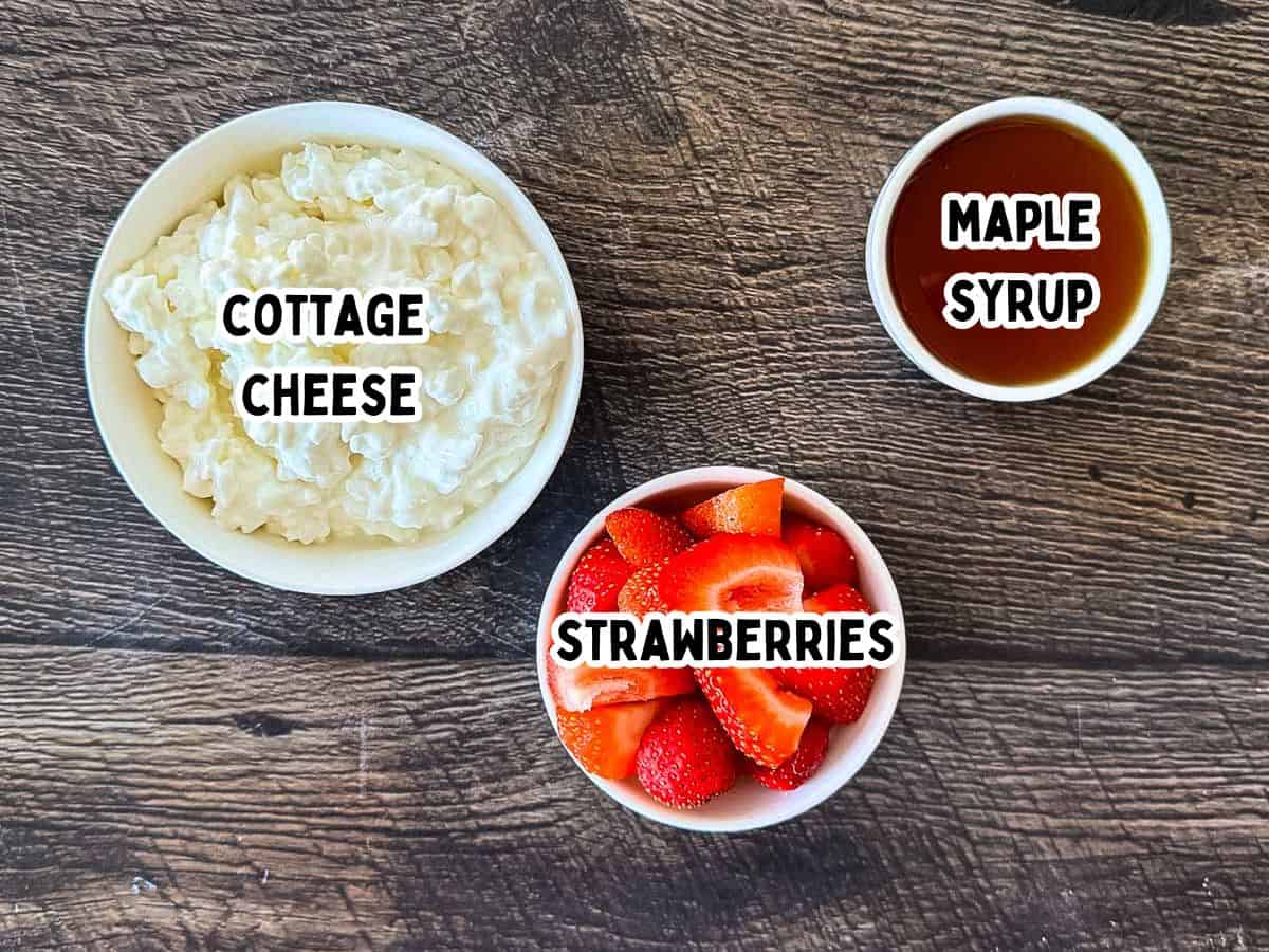 Labeled ingredients for Ninja Creami strawberry cottage cheese ice cream placed on wooden counter.