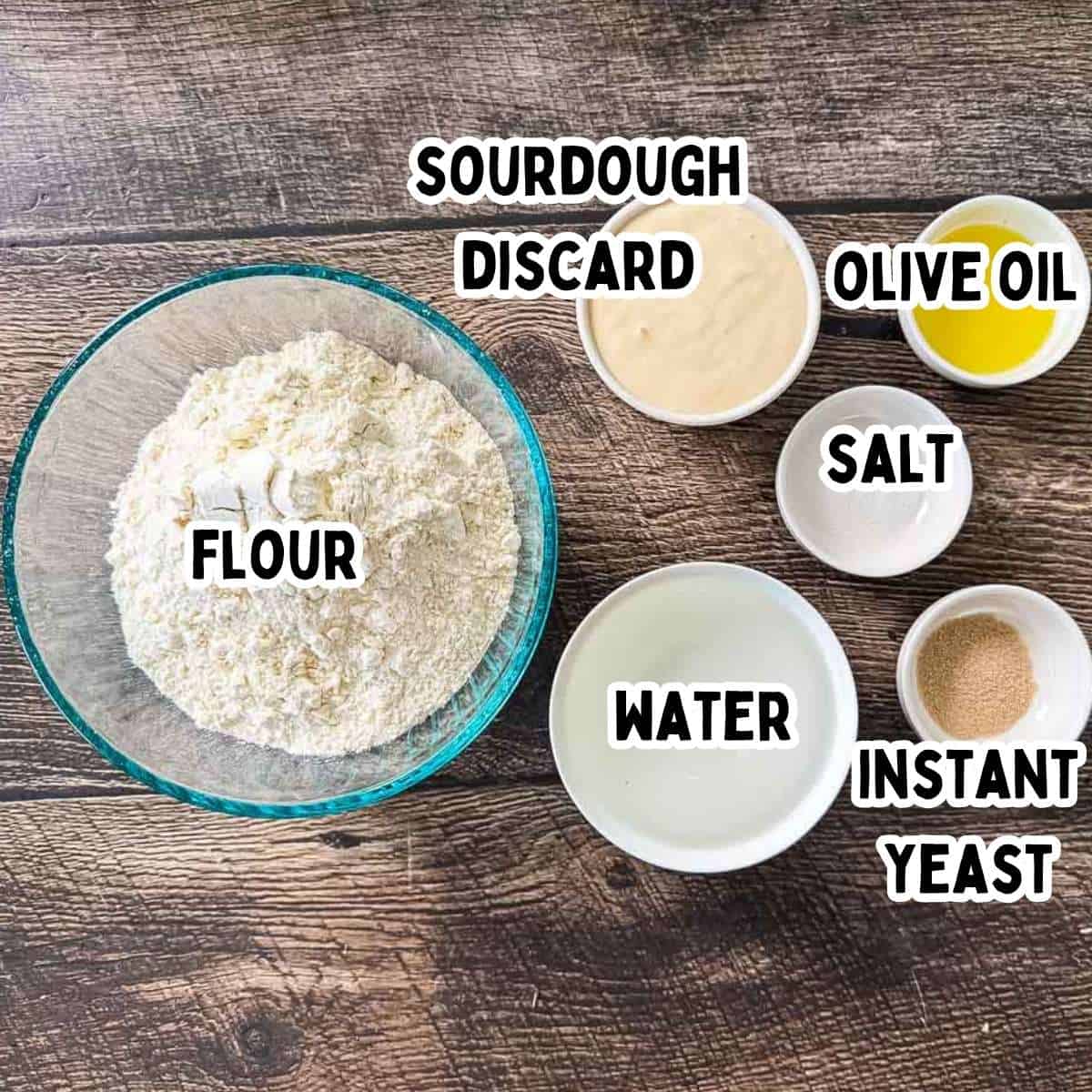 The labeled ingredients for sourdough discard sandwich bread on a wooden table.