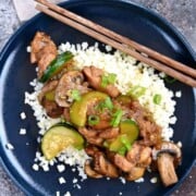 Instant pot chinese garlic chicken on a white plate with zucchini and chopsticks.