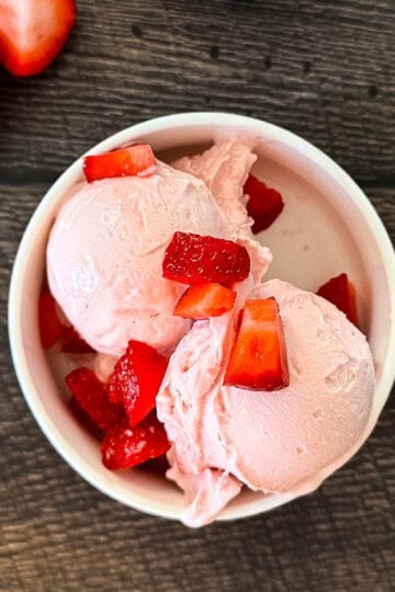 Creamy Ninja Creami strawberry cottage cheese ice cream made with cottage cheese and fresh strawberries in a white bowl.