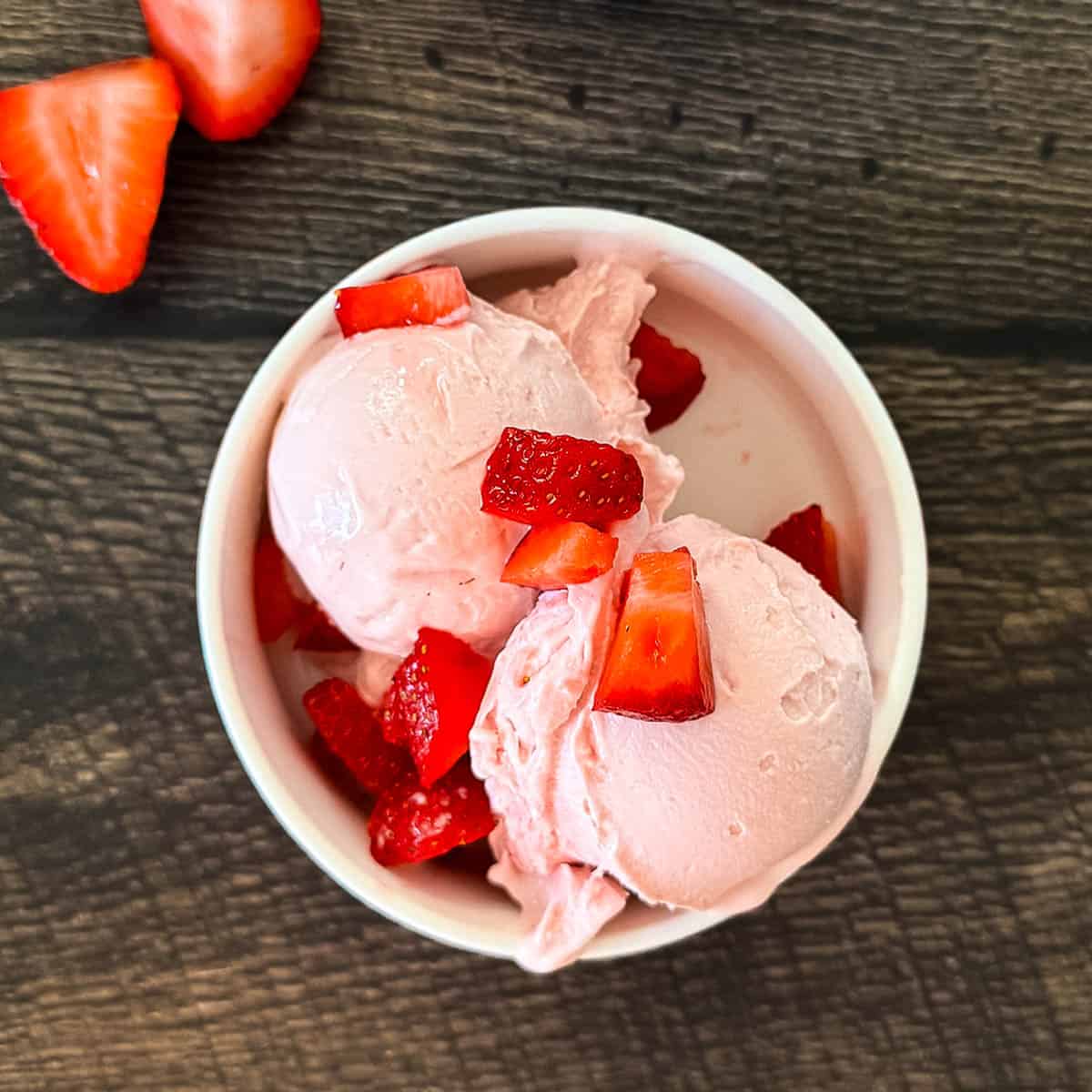 Creamy Ninja Creami strawberry cottage cheese ice cream made with cottage cheese and fresh strawberries in a white bowl.