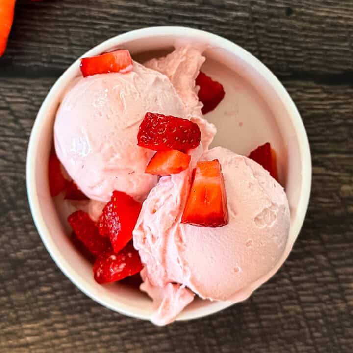 Creamy Ninja Creami strawberry cottage cheese ice cream made with cottage cheese and fresh strawberries in a bowl.