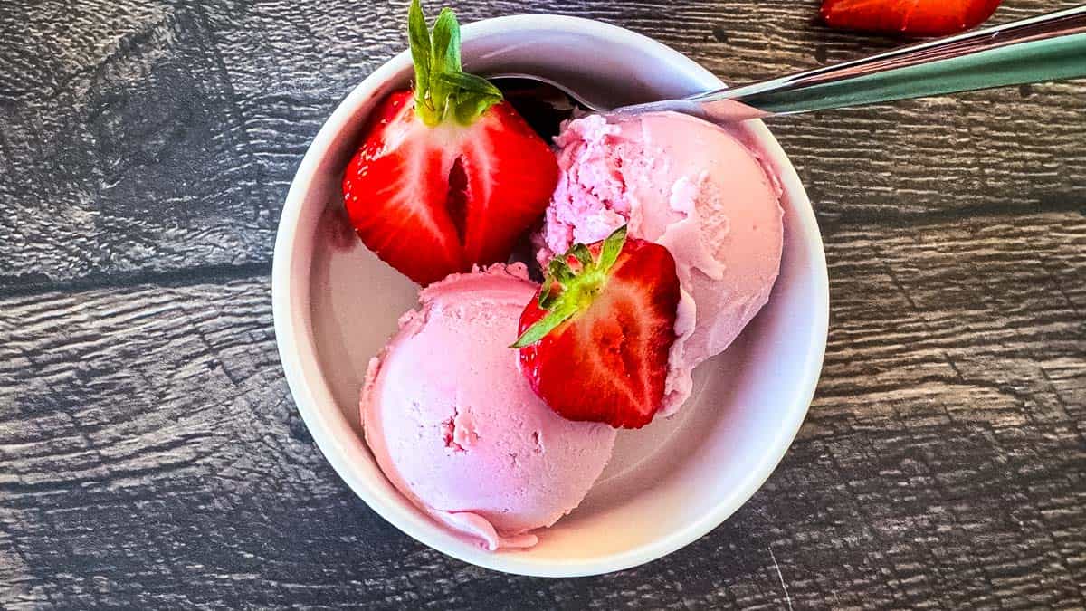 Two scoops of smooth pink Ninja Creami ice cream in a white bowl.