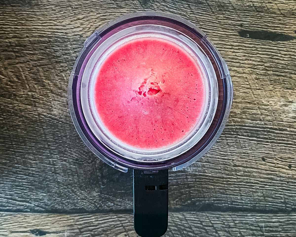 A frozen pint of blended pink strawberry ice cream base with a flat surface, ready to be processed in the Ninja Creami machine.