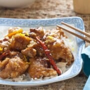 A plate filled with rice and orange chicken.