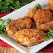 Homemade Shake and Bake chicken thighs on a white serving platter.