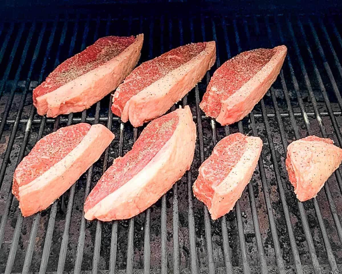 Raw smoked picanha steaks arranged on a pellet grill for smoking.