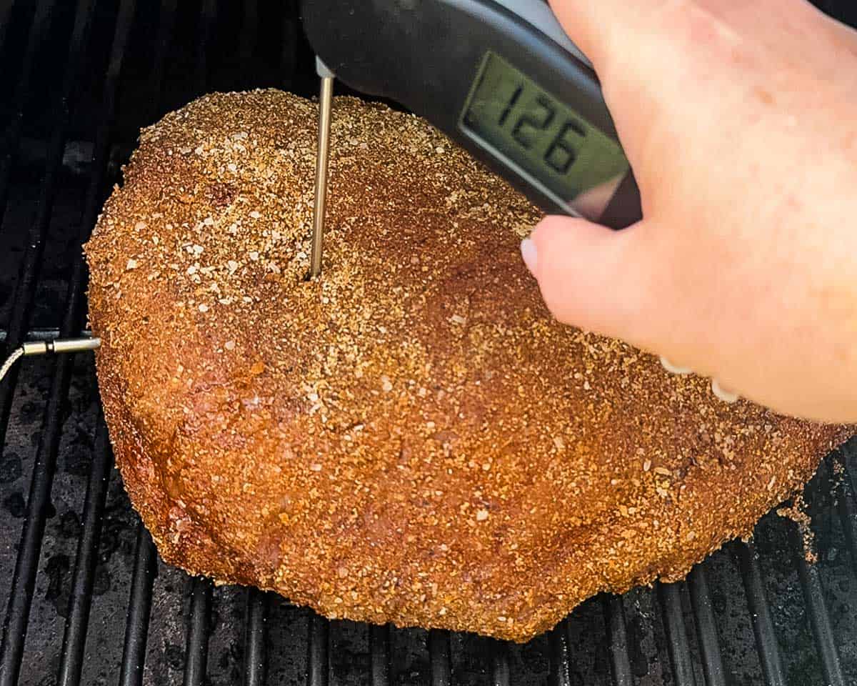 Checking the internal temperature of smoked picanha with a digital meat thermometer.