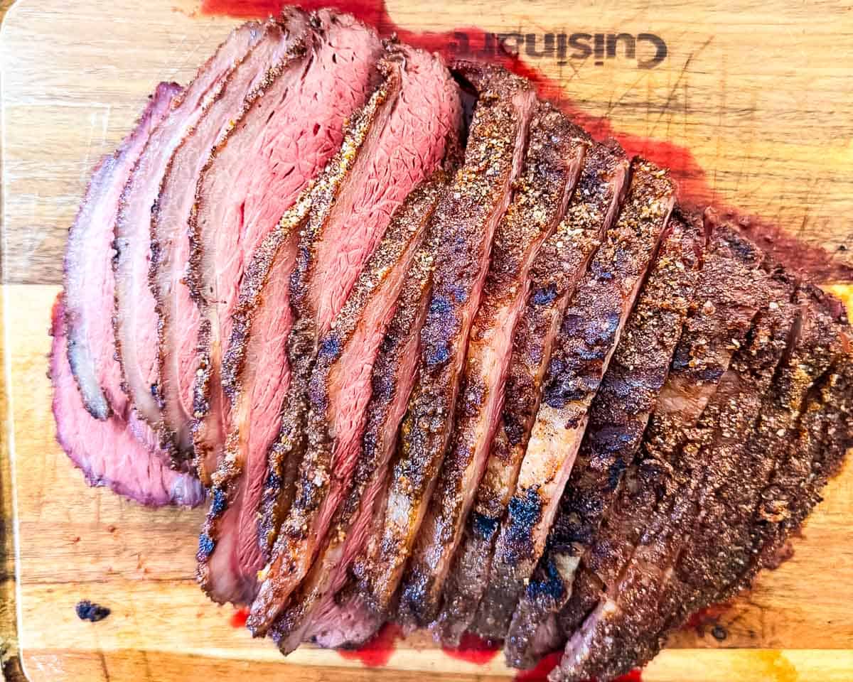 Sliced smoked sirloin cap roast with a juicy medium-rare center and smoky crust.
