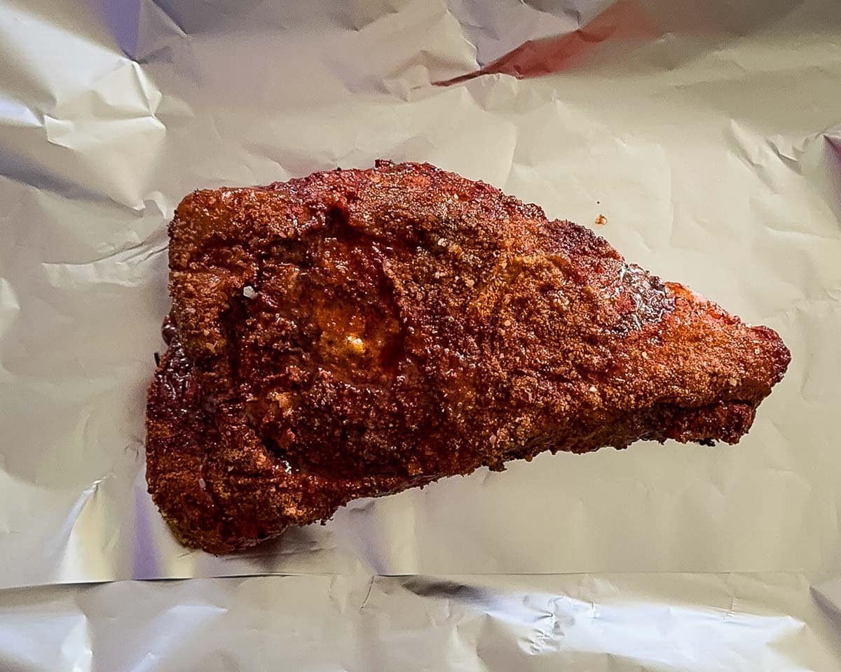 moked tri-tip roast with a dark bark resting on aluminum foil before adding beef broth and butter.