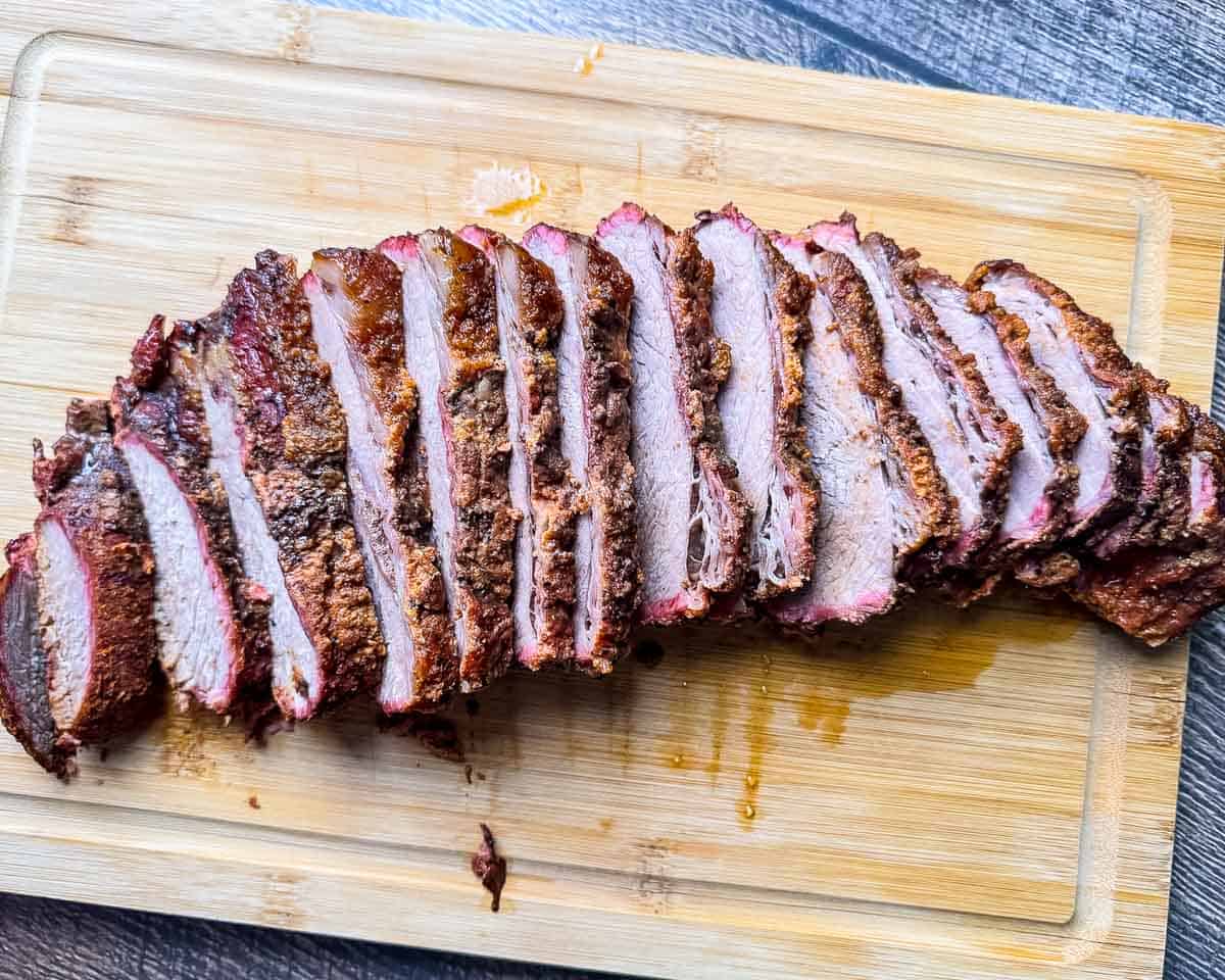 Close-up of sliced smoked tri tip cooked like brisket showing the bark, smoke ring, and juicy slices.