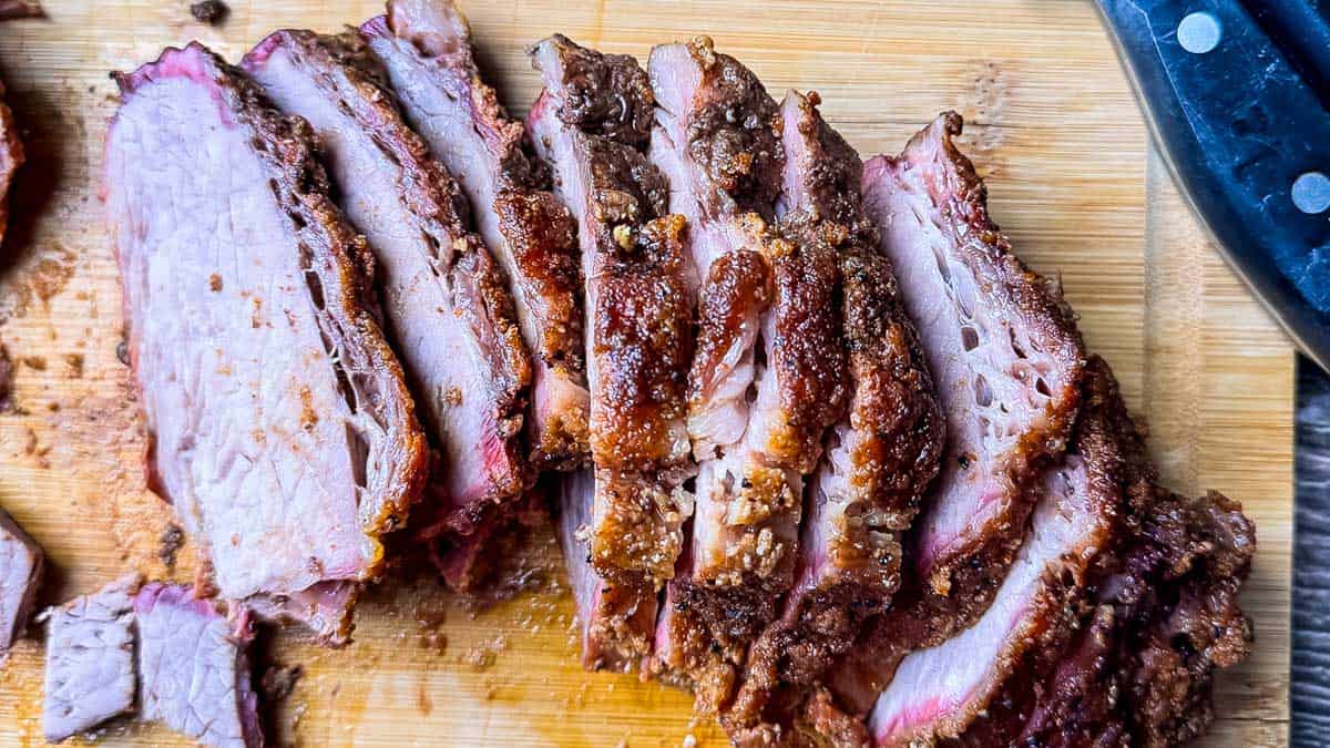 Close-up of sliced smoked tri tip cooked like brisket showing the bark, smoke ring, and tender slices.