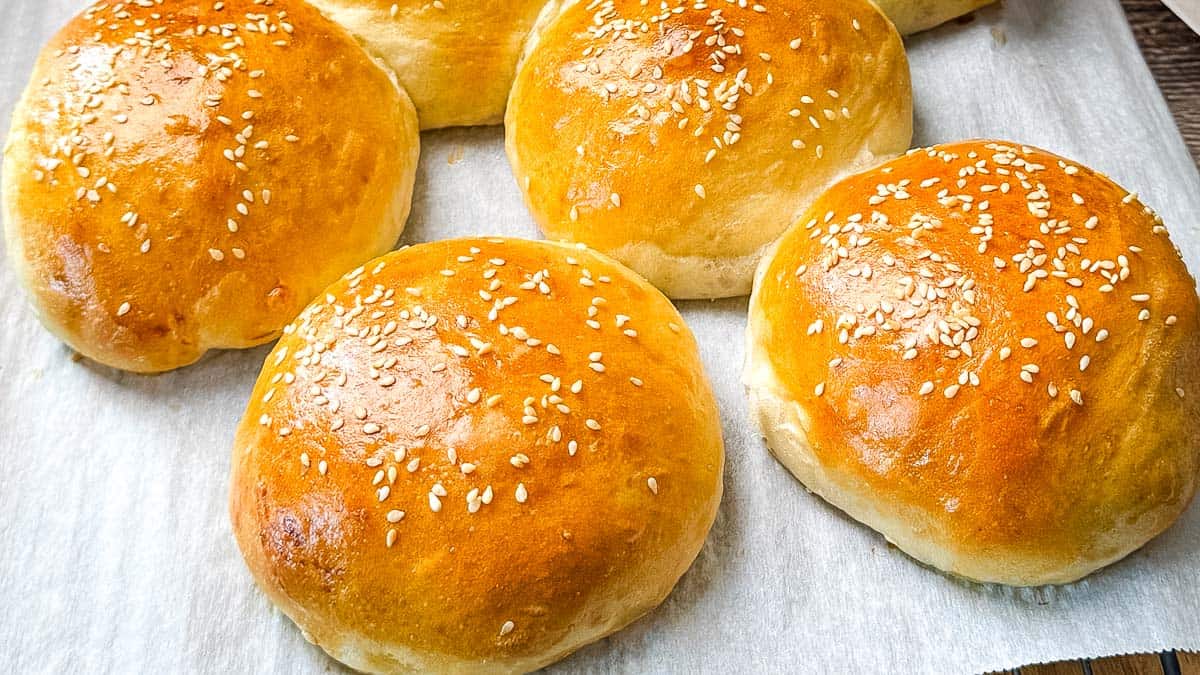 Freshly baked sourdough discard hamburger buns with golden brown tops and sesame seeds.