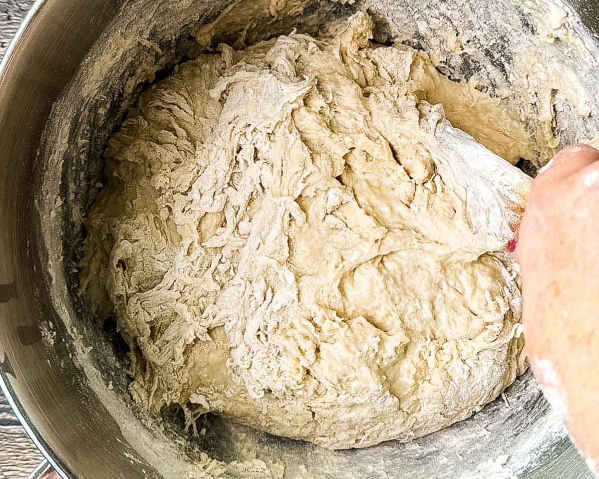 Stirring flour into the dough mixture for homemade sourdough hamburger buns.