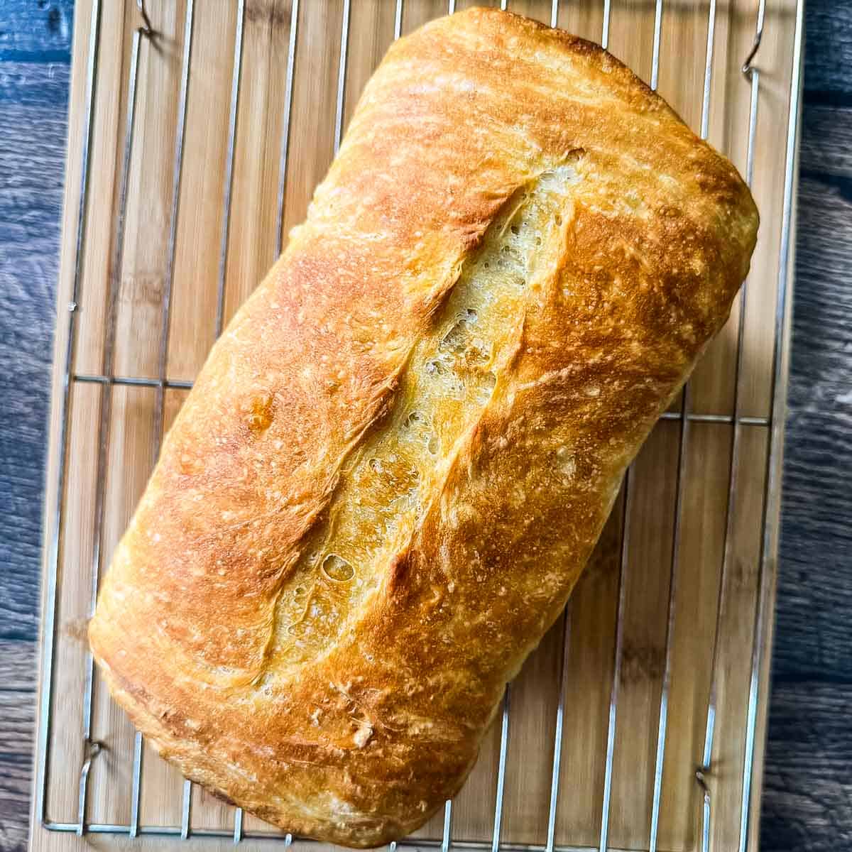 Freshly baked sourdough discard sandwich bread cooling on a wire rack with a golden brown crust and scored top.