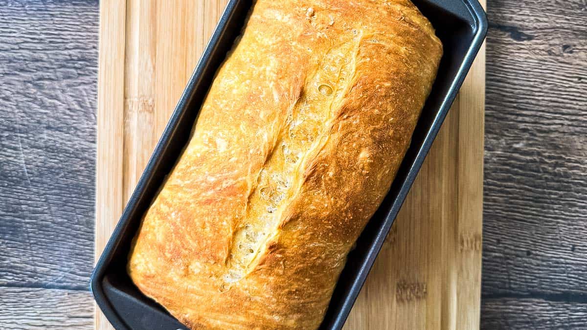 Freshly baked sourdough discard sandwich bread with a golden brown crust and scored top when it is removed from the oven.
