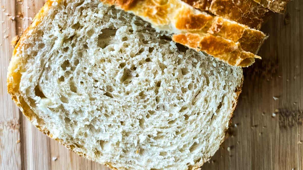 Soft sourdough discard sandwich bread sliced on a wooden cutting board showing a fluffy, tender crumb and golden crust.