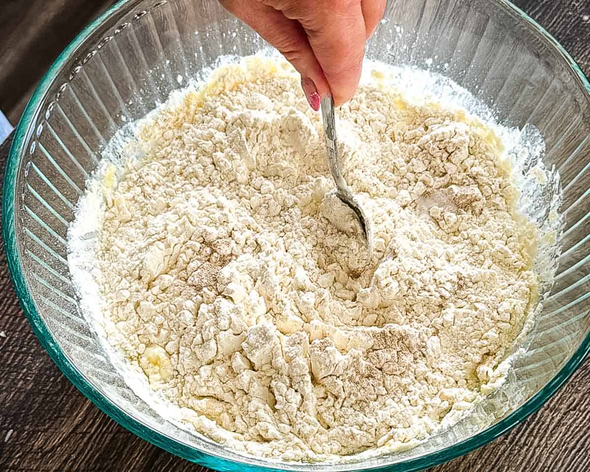 Using a spoon to mix the ingredients for same day sandwich bread in a large bowl.