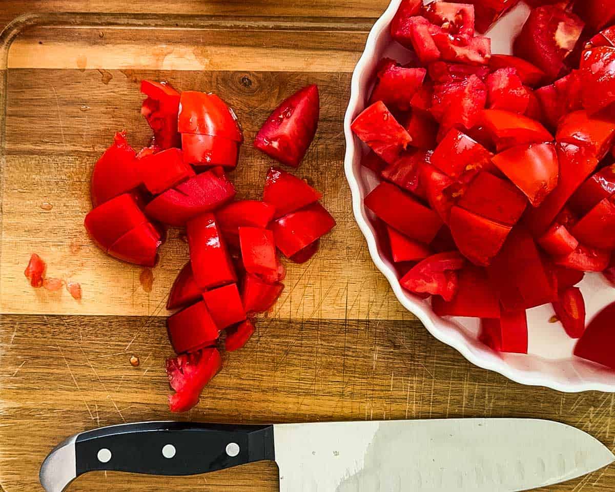 Chopped fresh Roma tomatoes on a cutting board, prepared for making homemade canned pizza sauce with fresh tomatoes.