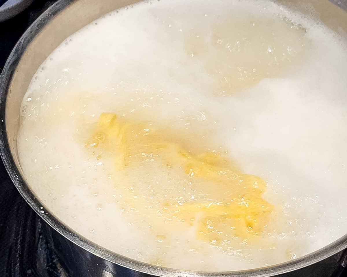 Fettuccine pasta cooking in a large pot of boiling salted water.