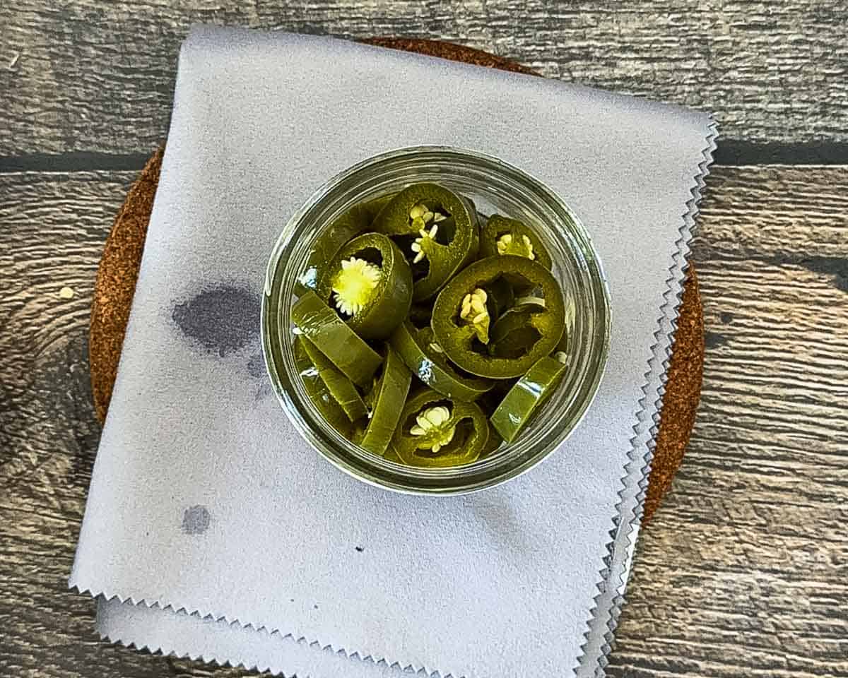 Sliced jalapeno slices in a canning jar with half a garlic clove.