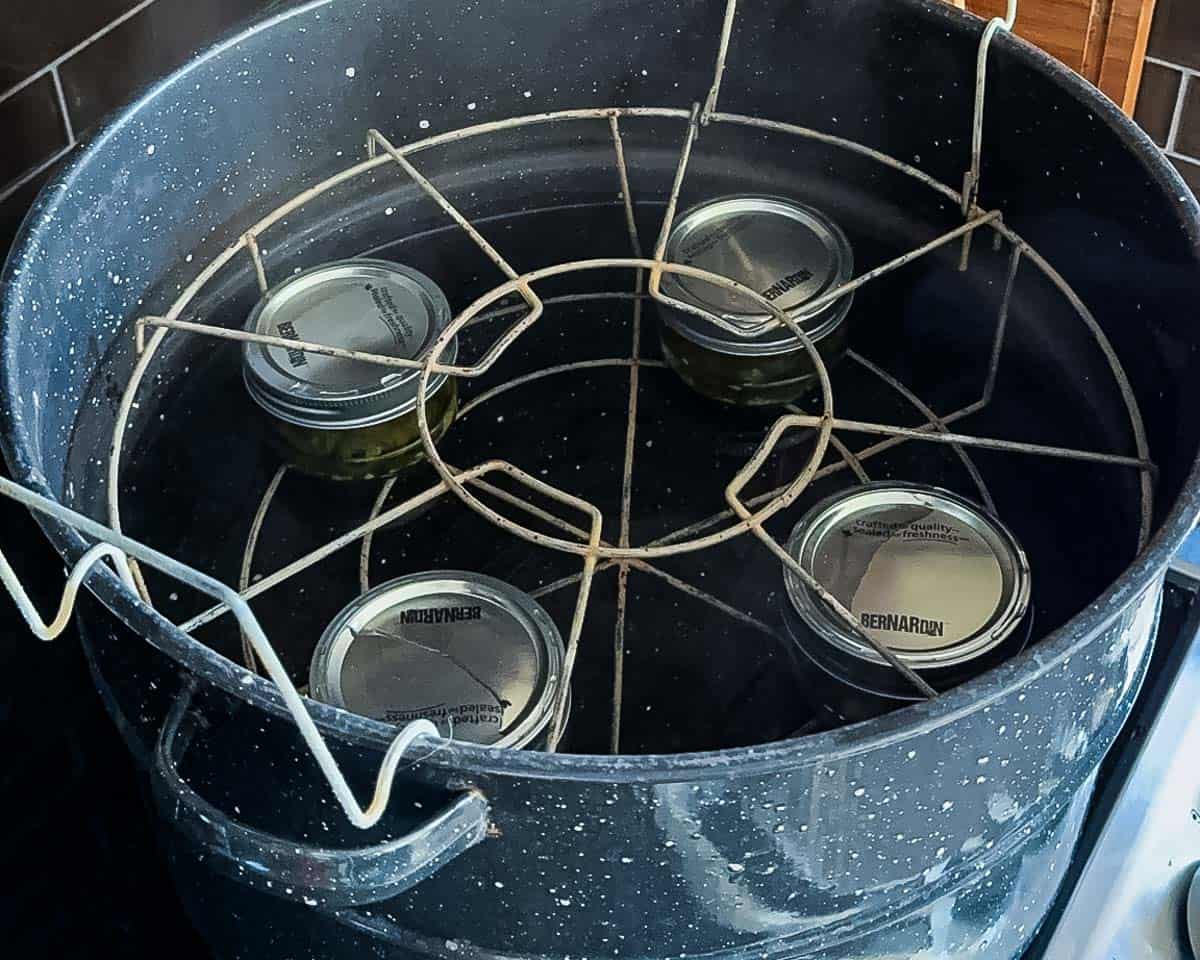 Jars of pickled jalapeño peppers processing in a boiling water bath canner.